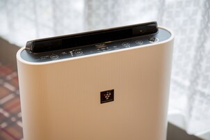 Un purificador de aire blanco con panel de control y un pequeño logo en la parte frontal.