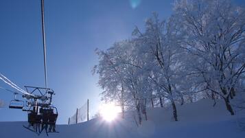 A ski lift with cables and chairs, a snowy landscape, and trees covered in snow.