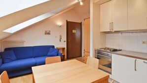 A compact living space with a dining area, kitchenette, and a blue sofa.