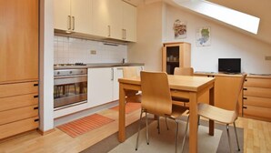 A modern kitchen with wooden cabinets, a built-in oven, and a dining area with a table and chairs.