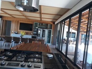 Enjoy cooking and dining in this well-equipped kitchen with a central island and dining table, featuring a range hood above the stove and oven and microwave.