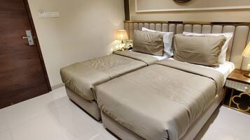 Una cama doble con ropa de cama color beige, una mesita de noche con una lámpara y una puerta de madera.