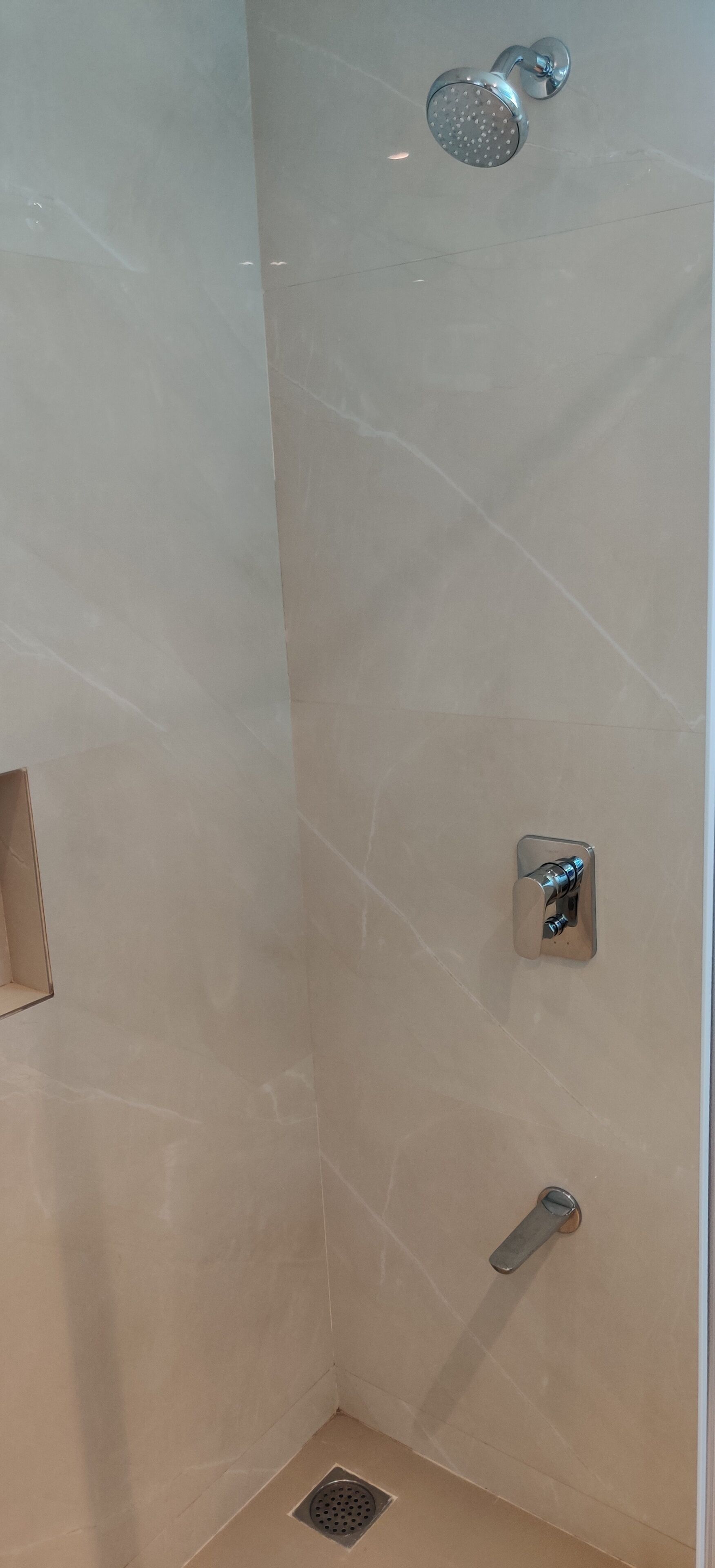 A modern shower with a handheld showerhead and a wall-mounted control panel.