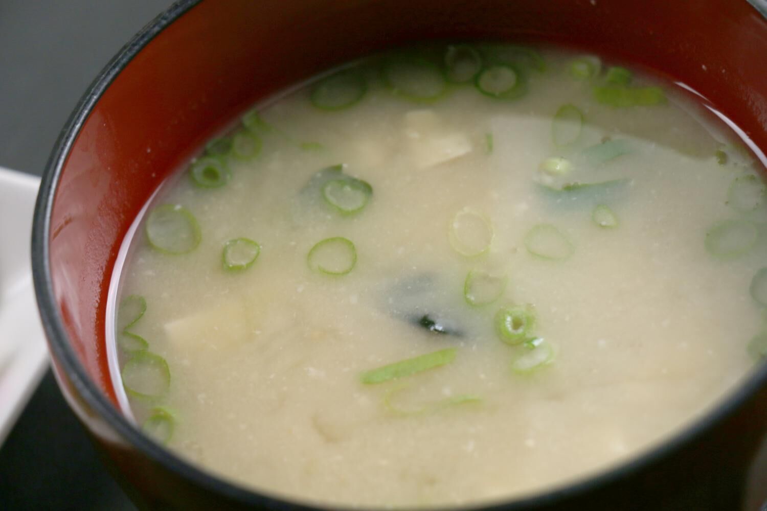 A bowl of soup with green onions.
