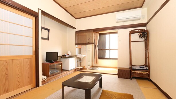 Una habitación japonesa tradicional con suelo de tatami, una mesa baja, un televisor y un futón.