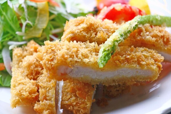 A plate of breaded and fried food, possibly chicken, with a green vegetable garnish. - Ryokan Kibun (Chikujo)