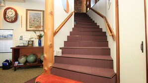 Una escalera con barandillas de madera y peldaños alfombrados que conduce a un segundo piso.
