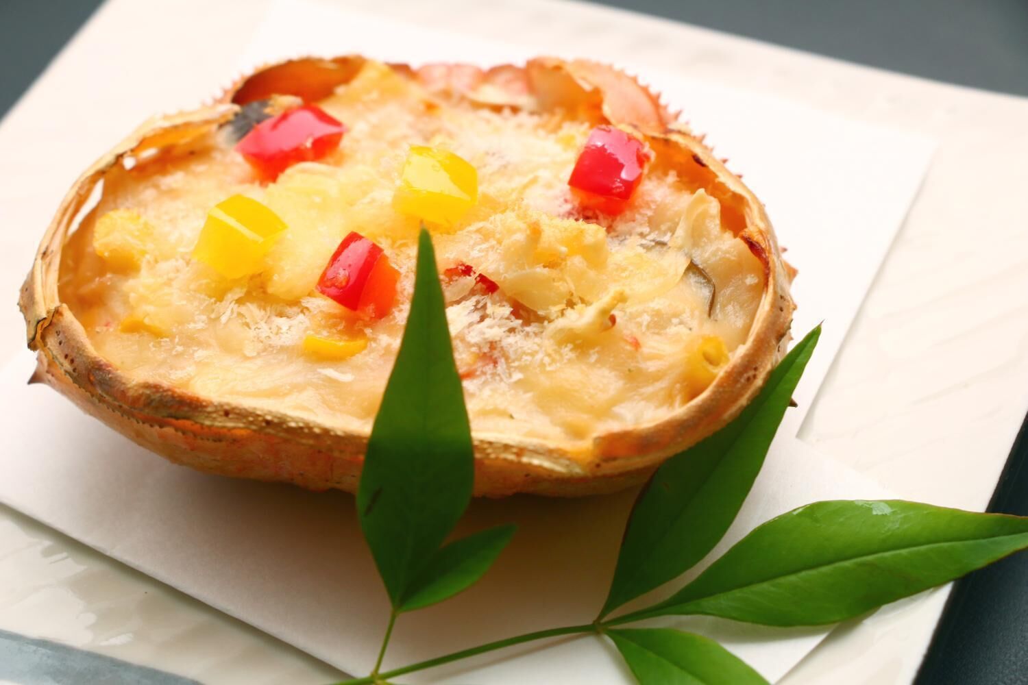Una tarta con corteza dorada y adornos coloridos, sobre un mantel blanco con hojas verdes.