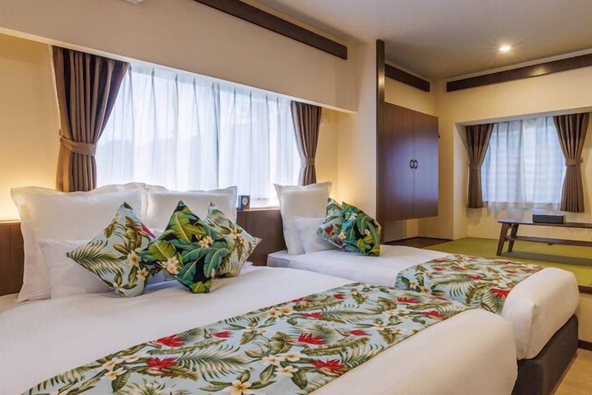 A hotel room with two beds, a desk, and a wardrobe.