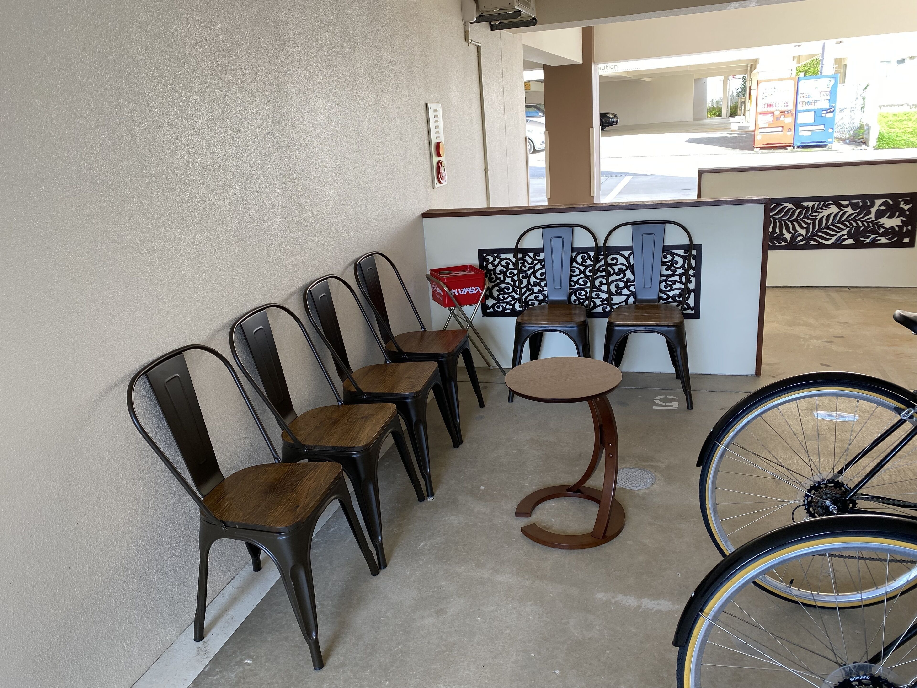 A seating area with metal chairs and a small round table, a bicycle, and a decorative wall panel.