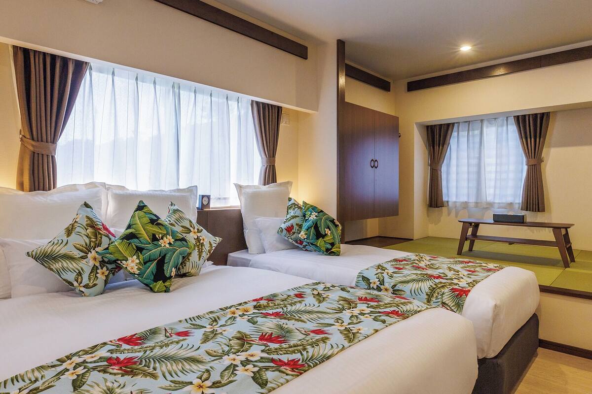 A hotel room with two beds, a desk, and a wardrobe.