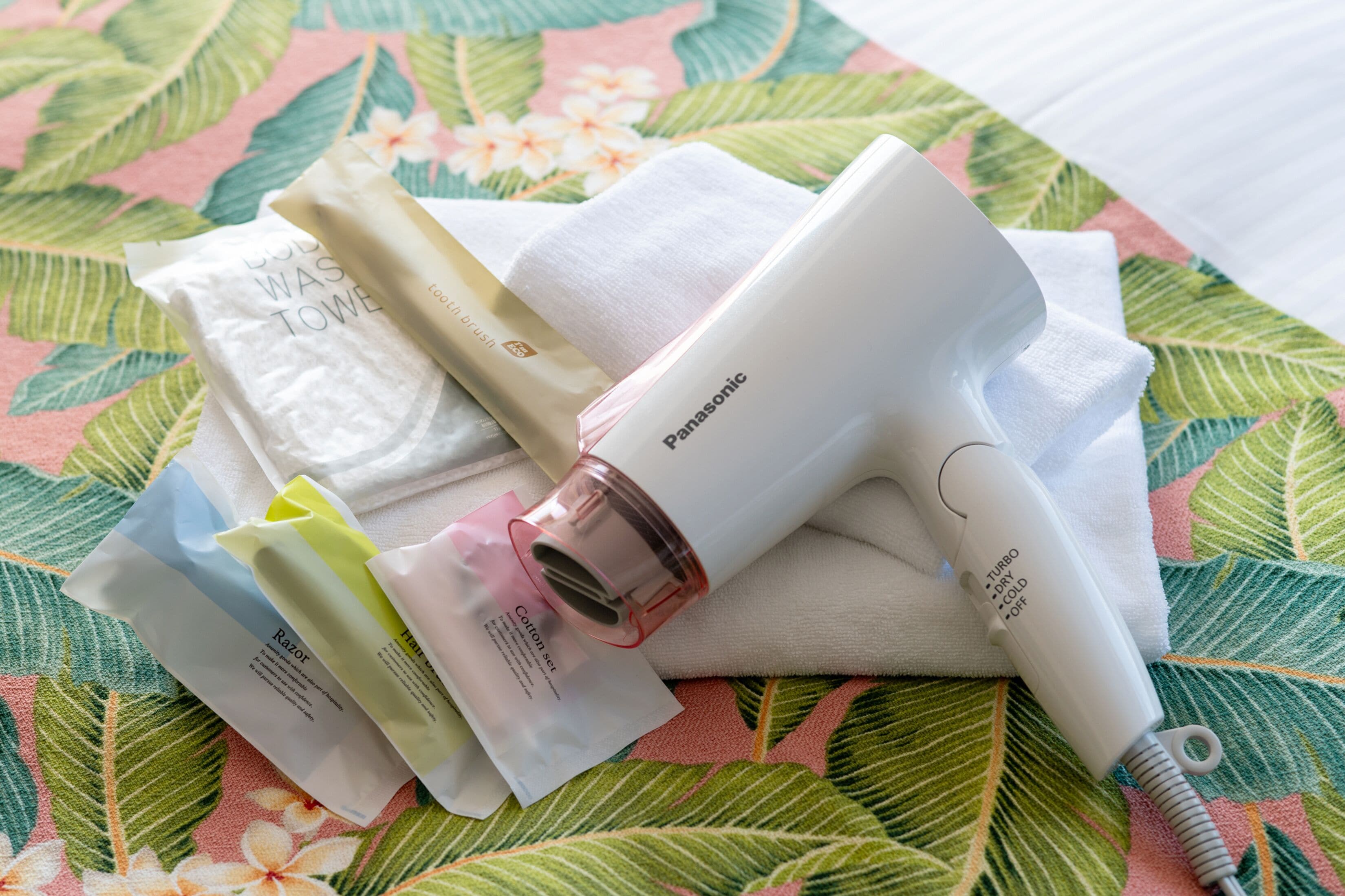 A Panasonic hair dryer and various personal care items on a floral-patterned surface.
