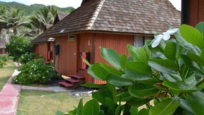 A wooden building with a sloped roof, surrounded by greenery and palm trees. - Hakamoui Plage (Ua Pou)