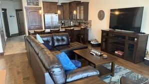 Ein modernes Wohnzimmer mit einem ledernen Ecksofa, einem Holztisch und einem Flachbildfernseher.