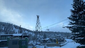 Ein verschneites Bergdorf mit Seilbahn, Häusern und einer Straße mit Geschwindigkeitsbegrenzung.