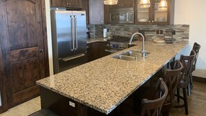 Eine moderne Küche mit Granit Arbeitsplatten, Edelstahlgeräten und dunklen Holzschränken.