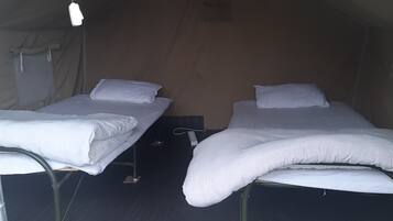 Two single beds with white bedding in a tent-like structure.