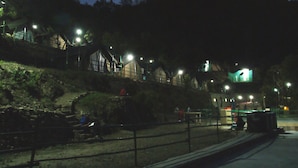 A nighttime view of a park with a stone wall, benches, and a pathway. - Camp Dogadda (Lansdowne)