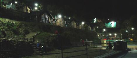A nighttime view of a park with a stone wall, benches, and a pathway.