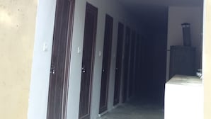 A corridor with doors on one side and a staircase leading to an upper level. - Camp Dogadda (Lansdowne)