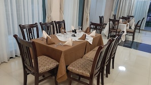 A dining area with a round table set for six, surrounded by wooden chairs with patterned cushions.