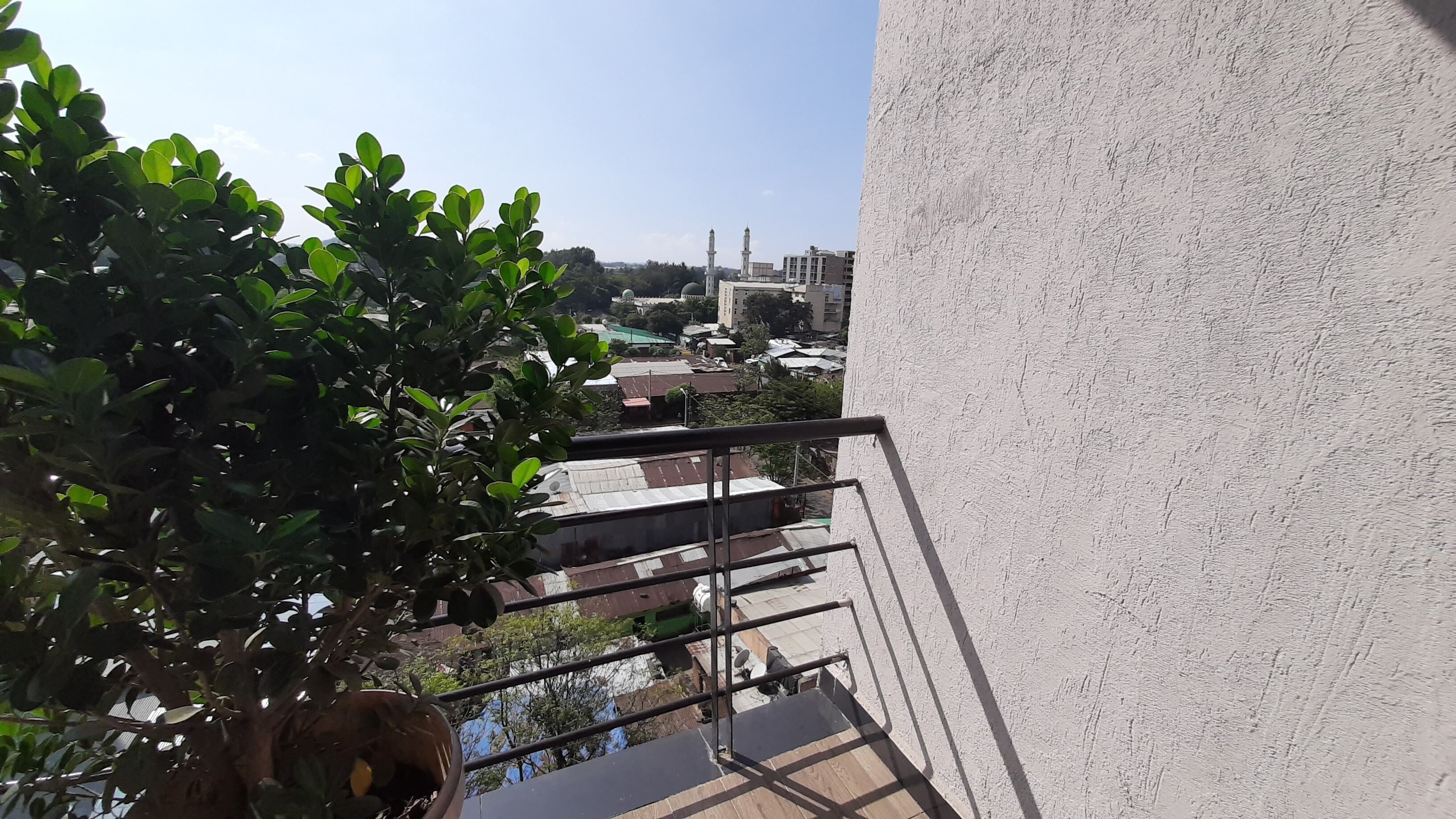 A balcony with a view of a cityscape, including buildings and a mosque.