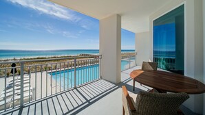 A balcony with a view of the ocean and a swimming pool.