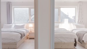 A bedroom with two beds, a nightstand, and a window with a view of buildings. - Sio Suite (Seoul)