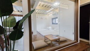 Une chambre moderne avec une cloison en verre, un banc en bois et une grande plante en pot.