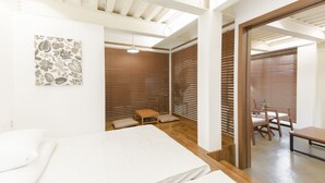 Une chambre moderne avec un lit, une petite table et une chaise. Il y a un mur en bois et une fenêtre avec des stores.