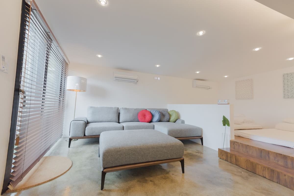 A modern living room with a grey sofa, a wooden coffee table, and a small wooden bench.
