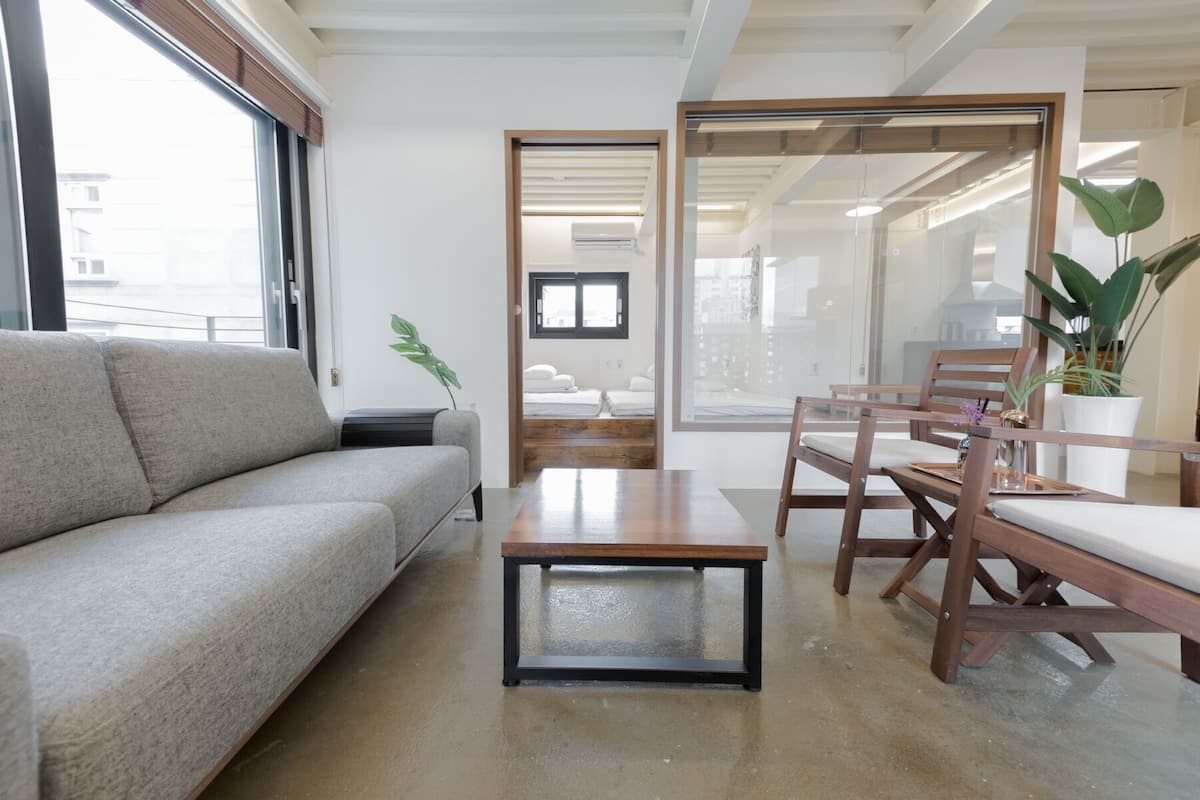 A modern living room with a sofa, a coffee table, and a dining area with chairs and a table.