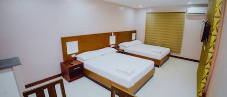 A hotel room with two beds, a wooden table, and a small desk with a chair.