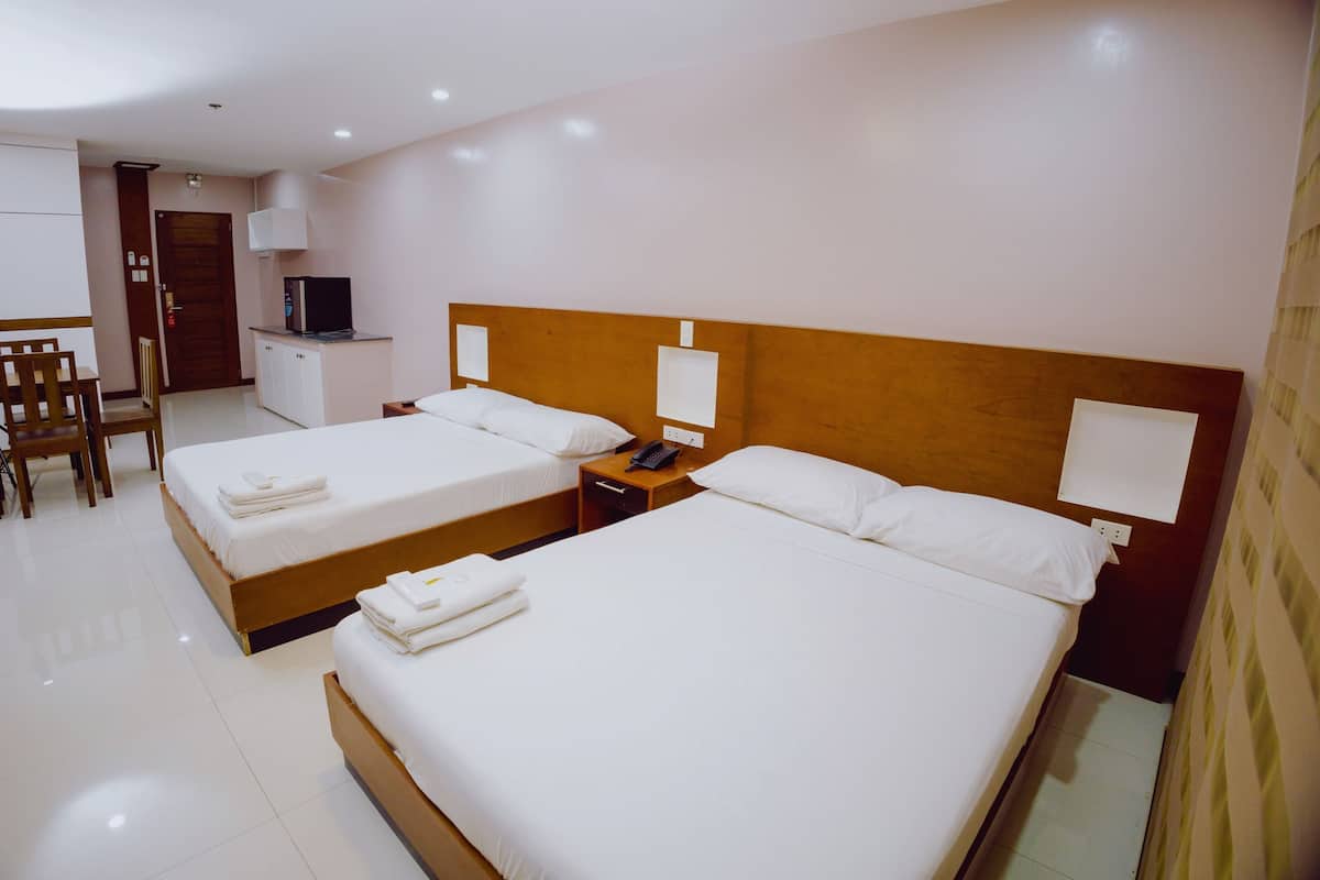 A hotel room with two beds, a desk, a chair, a TV, and a wardrobe.
