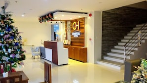 A modern hotel lobby with a reception desk, a Christmas tree, and a staircase. - Coastal Hotel Iloilo (Leganes)