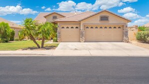 A single-story house with a beige facade, a stone accent wall, and a garage with a beige door. - Heated Pool 88 degrees No Fee and Golf Course View! (Avondale)