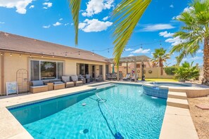 A swimming pool with a sunken hot tub, lounge chairs, and a covered patio area.