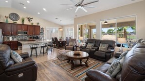 A spacious living room with leather sofas, a coffee table, and a dining area with chairs. - Heated Pool 88 degrees No Fee and Golf Course View! (Avondale)
