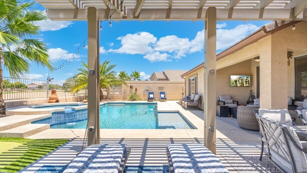 A backyard with a swimming pool, lounge chairs, and a pergola. - Heated Pool 88 degrees No Fee and Golf Course View! (Avondale)
