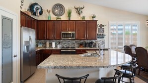 A kitchen with granite countertops, wooden cabinets, a stainless steel refrigerator, a microwave, and a sink. - Heated Pool 88 degrees No Fee and Golf Course View! (Avondale)