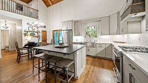 Une cuisine spacieuse dotée d’un îlot central, de parquets en bois et d’un plafond haut avec des poutres apparentes.