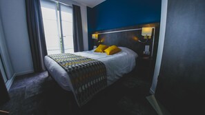 A hotel room with a bed, a nightstand, a lamp, and a window with curtains. - Hôtel du Tramway (Laon)