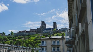 A historic building with a prominent tower and a cathedral in the background. - Hôtel du Tramway (Laon)