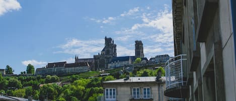 Un edificio histórico con una torre destacada y una catedral al fondo.