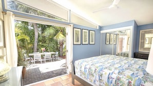 Ein Schlafzimmer mit Bett, Schreibtisch und Blick auf eine Außenpatio mit Stühlen und Pflanzen.