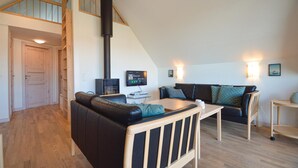 Una sala de estar acogedora con un sofá de cuero negro, una mesa de centro de madera, un televisor y una chimenea.