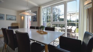 Un comedor con una mesa grande, sillas y vistas al exterior a través de amplios ventanales.