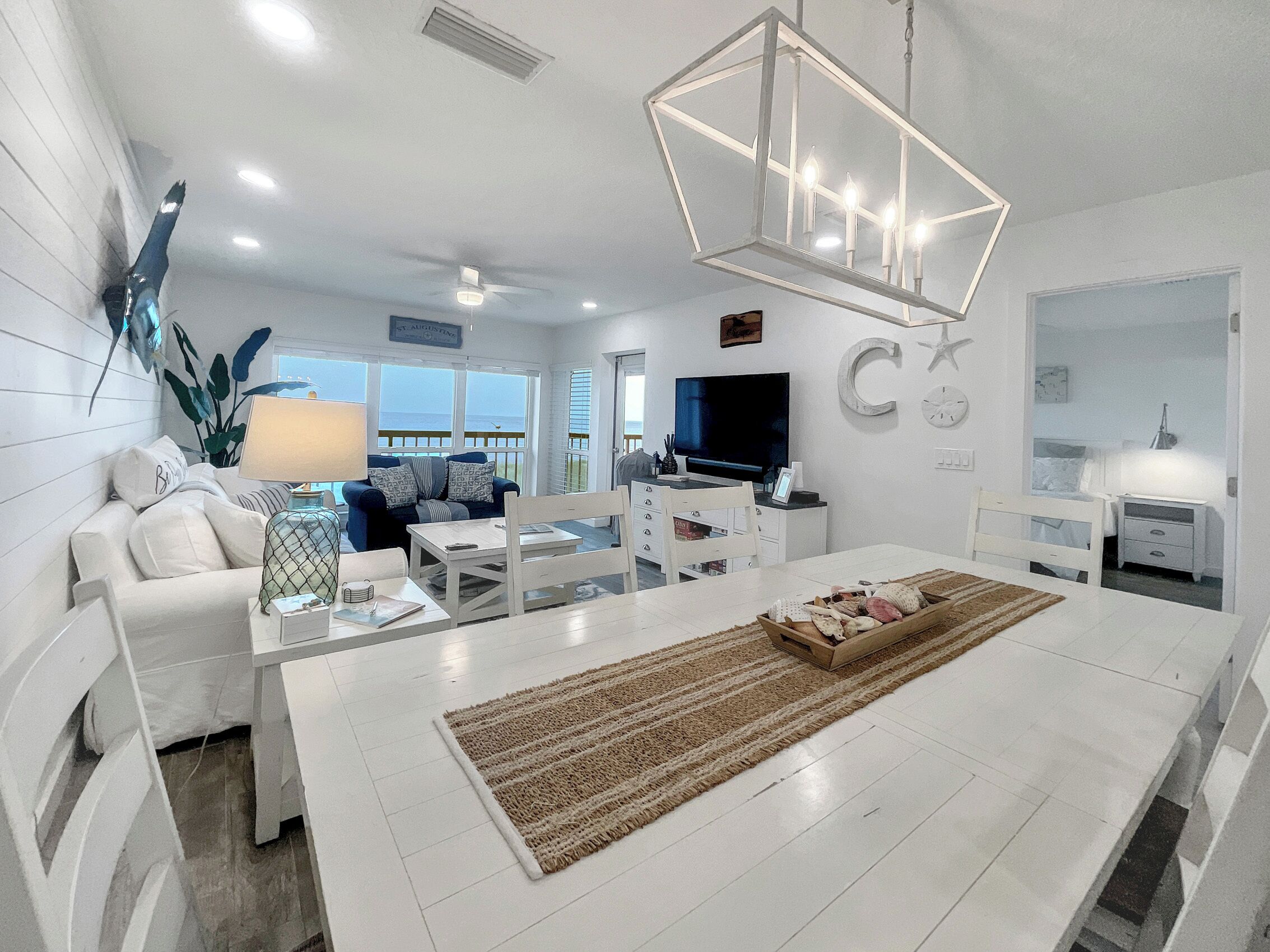 A modern living room with a white sofa, a dining table, and a kitchen area.