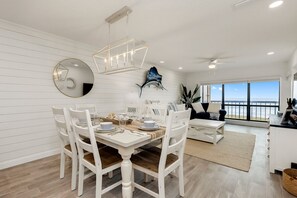 Enjoy meals with a view of the ocean from this dining area, featuring a large window and a stylish light fixture.