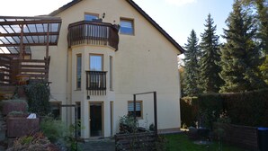 A two-story house with a balcony, a covered porch, and a well-maintained garden. - Living in the countryside (Dresden)